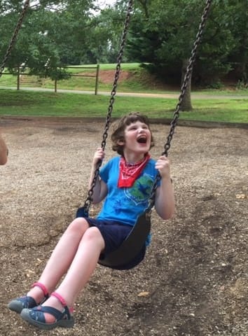 Child riding on a swing with a big smile. Image taken from CV Momifesto