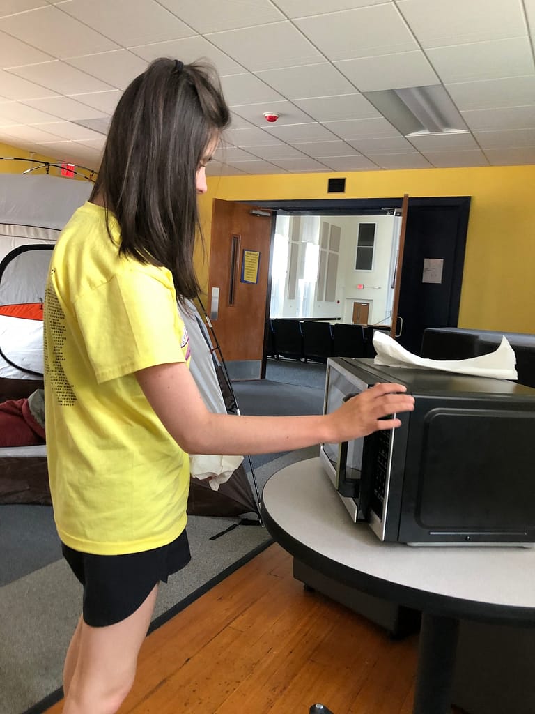 Blind middle school girl explores a microwave as part of a smore making activity at school for sensory efficiency ECC instruction.